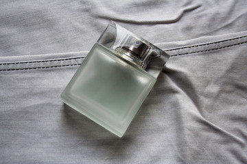 Rectangular perfume bottle with frosted glass effect on light grey jeans