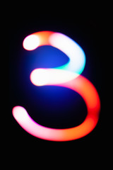Digit 3. Three. Glowing numbers on dark background. Abstract light painting at night. Creative artistic colorful bokeh. New Year. Use it for build you own design for book cover, poster or post card.