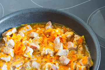 Meat with vegetables is stewed in a frying pan