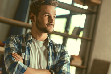 Hmm let me think. Handsome young man crossing his arms and looking into vacancy with a smile on his face while thinking about something pleasant.