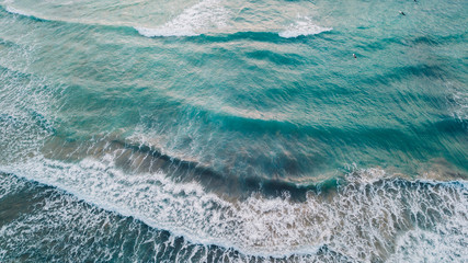 Scenic aerial drone view of beautiful turquoise mediterranean sea with waves and foam. Surfers with surfoards catching waves. View from above.