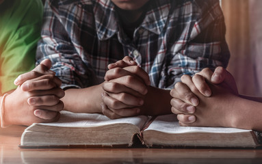 Children group praying on wooden table with open holy bible, prayer meeting concept