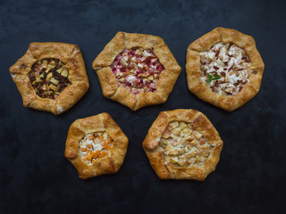 Pattern of different handmade pies on a black kitchen table.
