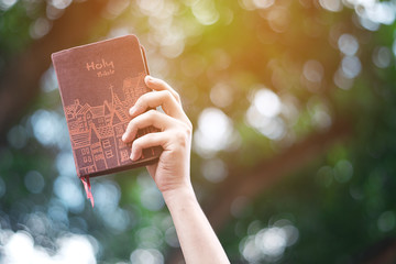 A woman is holding and hug the bible in the morning. Hands folded in prayer on a Holy Bible in life...
