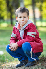 Fototapeta premium Absolutely quiet boy sitting in park on earth, tired child resting, portrait