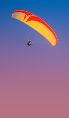 Beautiful yellow and red paraglider flying in colorful sky