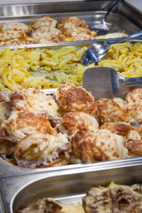 Cooked fried meat in batter and potatoes on the counter in the supermarket