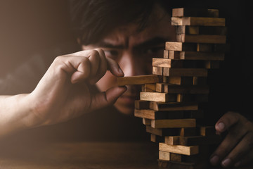 business man try to build wood block on wooden table and black background business organization...