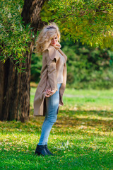 Beautiful elegant woman standing under the tree in autumn park