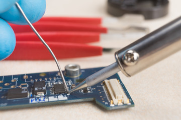 The hand holding the tin, a soldering iron solder the chip in place. Computer repair....