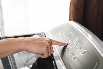 Close up young man hand pressing start button on washing machine.