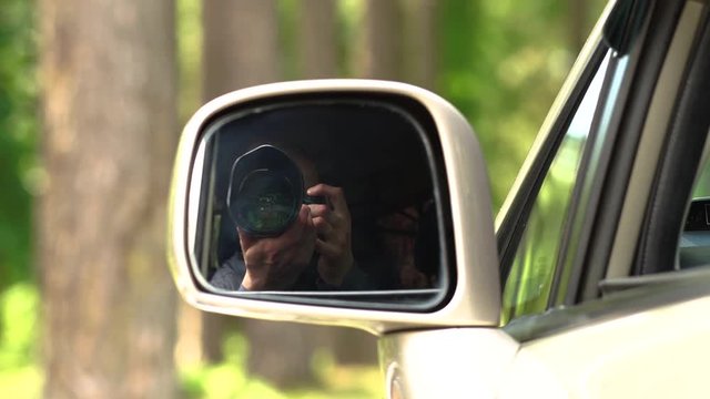 View From A Side Mirror Of An Auto - Young Male Photographer Takes A Camera With A Zoom Lens And Takes Pictures Of The Summer Nature Without Leaving The Car.
