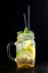 Bright green lemonade cocktail garnished with lemon and mint on black background