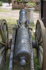 An old antique cannon with numerous decorations, coat of arms and beautiful handles.