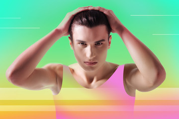 Male model. Handsome serious young man standing against colorful background while touching his hair