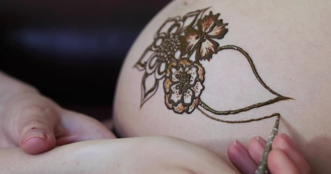 Drawing a mehendi on the stomach