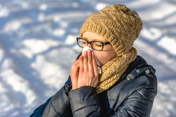 Sneezing woman blowing her nose with a tissue. Concept of people with cold and flu in winter with...