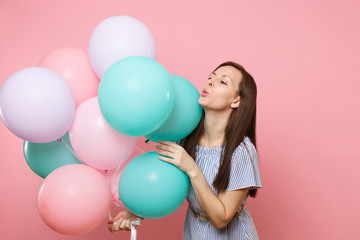 Fototapeta na wymiar Portrait of fascinating young tender woman wearing blue dress holding colorful air balloons isolated on bright trending pink background. Birthday holiday party, people sincere emotions concept.