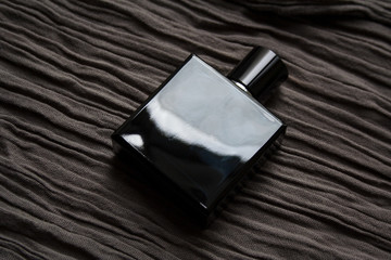 Dark blue glass perfume bottle isolated on textured hazel fabric