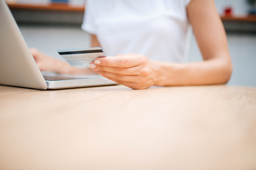 Woman using credit card and laptop. Close-up, copy space.