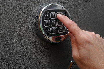 Hand enters combination on digital lock on a safe