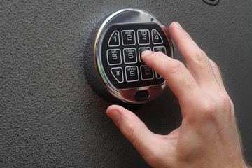 Hand enters combination on digital lock on a safe