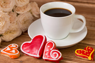 Valentine's day . Cup of coffee , flowers, Gingerbread Heart with icing on wooden background