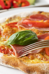 Detail einer Pizza mit Schinken und Basilikum