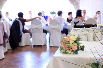 Bukiet ślubny na sali weselnej z gośćmi.