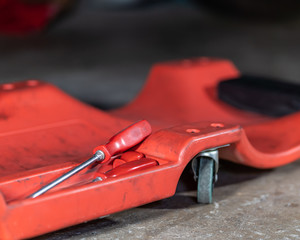 Auto repair shop tools on a creeper in a garage