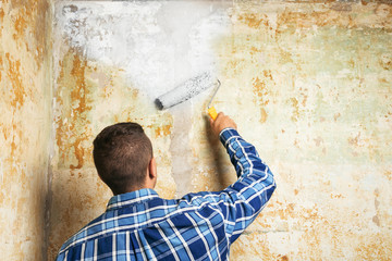 Obraz na płótnie Canvas The man paints the walls with white paint