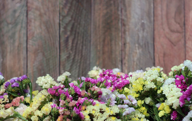 Kermek (limonium) yellow, pink and blue blooming flowers, wooden background