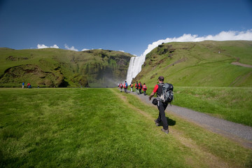 Grupo de personas caminando hacia la cascada de Skógafoss en Islandia