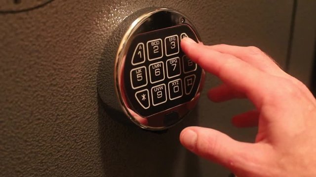 Hand enters combination on digital keypad lock on a safe