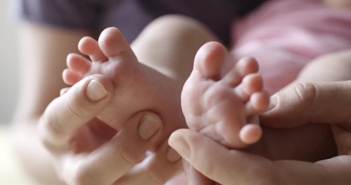 Crop view of young mom doing foot massage to her newborn baby