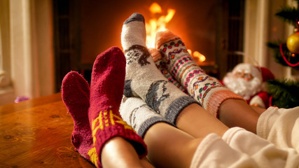 Family wearing warm knitted socks relaxing at house with burning fireplace