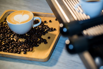 Focused coffee cup on wood tray with coffee beans and spike on background. daily aroma drinking concept. coffee latte art image for decoration, interior design background, wallpaper and copy space.