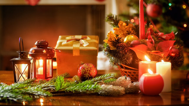 Closeup photo of golden Christmas gift box against burning fireplace and Christmas tree