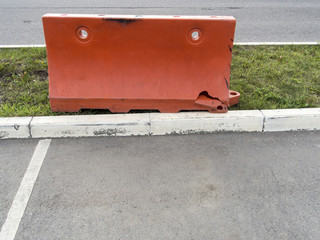 Red road block on a green lawn near a road