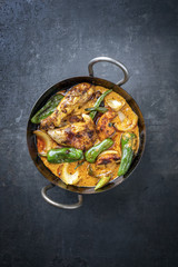 Traditional Thai kaeng massaman coconut chicken curry with jalapeno, poblano chili and sweet potatoes as top view in a traditional bowl