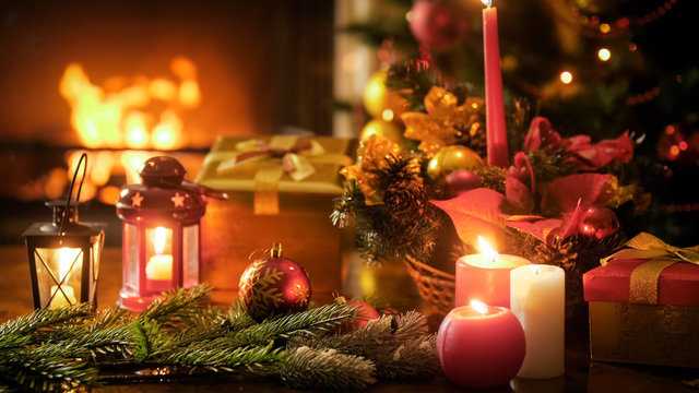 Closeup image of wooden table decorated for Christmas against burning fireplace at living room