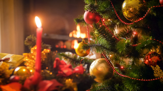 Closeup image of Christmas tree branches against candles and burning fireplace