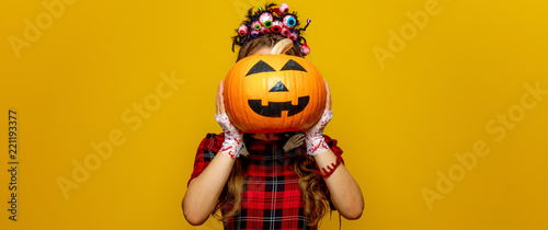 woman with halloween pumpkin in front of face isolated on yellow