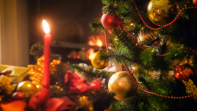 Closeup image decorated beautiful Christmas tree against burning fireplace at living room