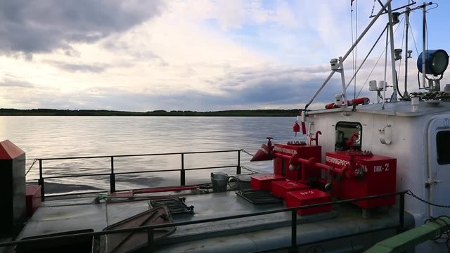 On board on small car ferry across the northern Sukhona River, the influx of the Severnaya Dvina in the north of Russia during the sunset.