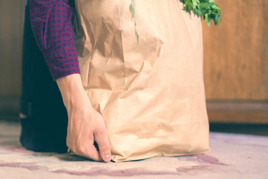 hands put the paper bag with fresh food on floor at home