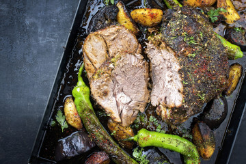 Barbecue marinated lamb roast with vegetable and potatoes as top view on a metal sheet