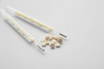 pills and thermometer on a white background