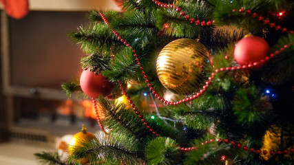 Closeup image of decorated by colorful baubles Christmas tree at night