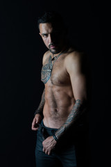 Man with tattoo design on skin. Bearded man shirtless with fit torso. Fashion model buckle leather...